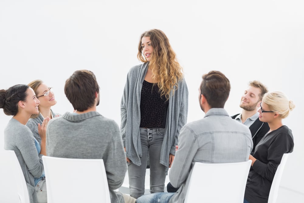 Group therapy in session sitting in a circle with therapist